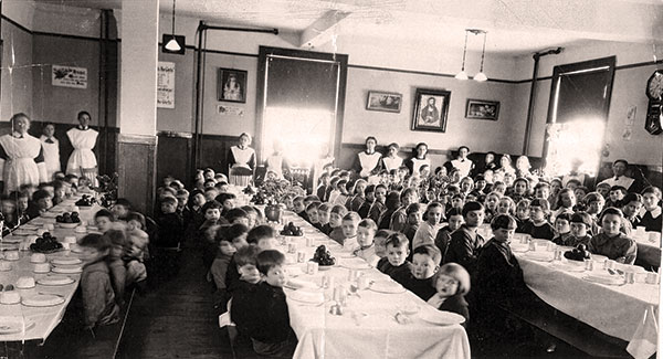 Children seated for dinner at three long tables.