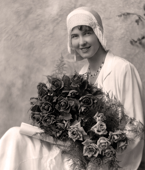 Elinor F. E. Black posing with a bouquet of roses.