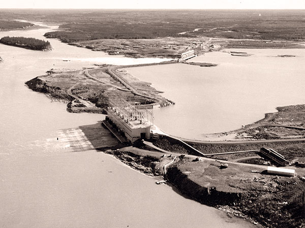 Aerial view of the completed  Kelsey Generating Station with its powerhouse in the foreground and spillway in the background.